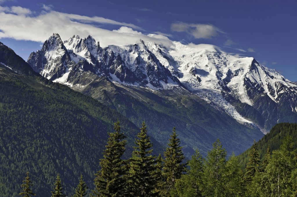The snow capped summit of Mont Blanc (4808m) overlooking the green summer forests of the Chamonix valley, Haute-Savoie, France. ProPhoto RGB profile for maximum color fidelity and gamut.